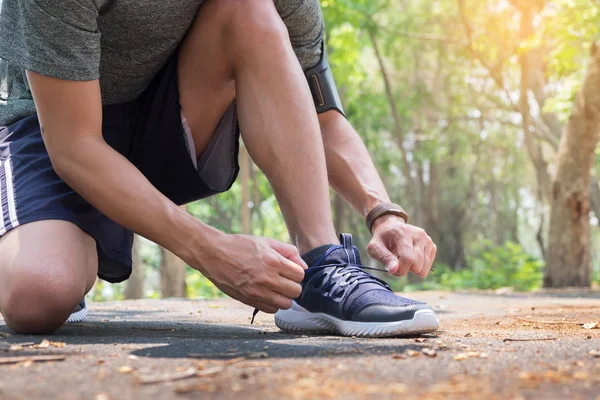 Recortado tiro de hombre joven corredor apretando los cordones de zapato de correr , —  Fotos de Stock