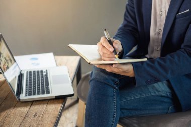 Düşünceli genç iş adamı rahat gömlekli not defteri tutan  