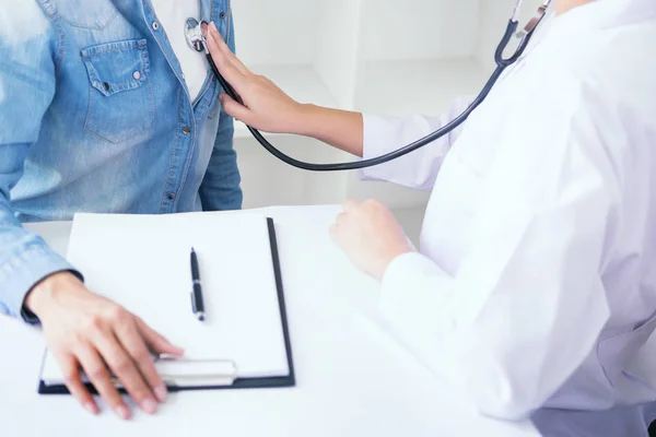 Médico escuchando alegres pacientes jóvenes pecho con estetoscopio — Foto de Stock