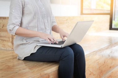Kütüphane içinde laptop ile katta oturan genç kadın