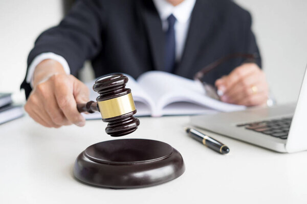 Адвокат-мужчина в зале суда стучит молотком по звучанию
 