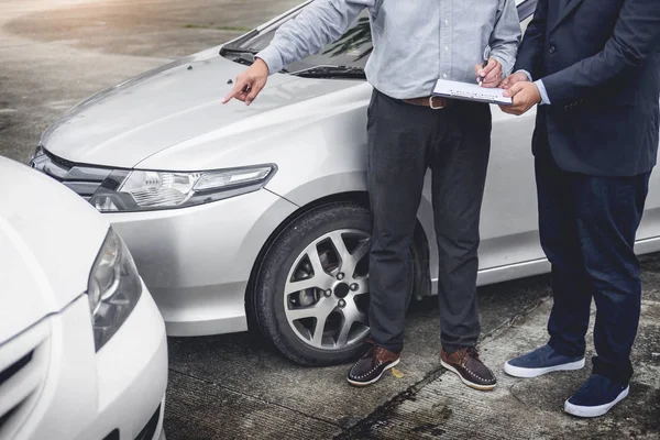 Agente de seguros que escribe en el portapapeles mientras examina el coche después de un — Foto de Stock