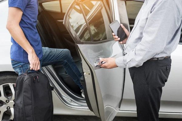 Motorista de táxi cumprimentando seus passageiros com sua bagagem no si — Fotografia de Stock