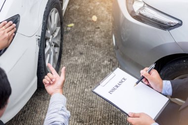 Insurance agent writing on clipboard while examining car after a clipart