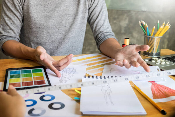 две молодые женщины, работающие модельерами и рисующие эскизы
