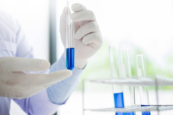 Asian scientific researcher working in laboratory holds test tub