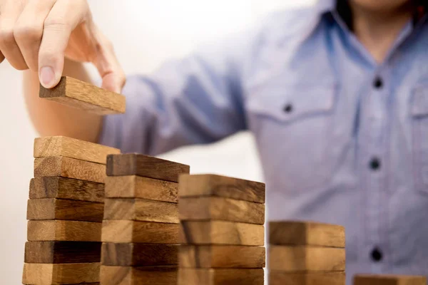 Ділова людина вручну кладе дерев'яні блоки, організовуючи укладання для розробника — стокове фото