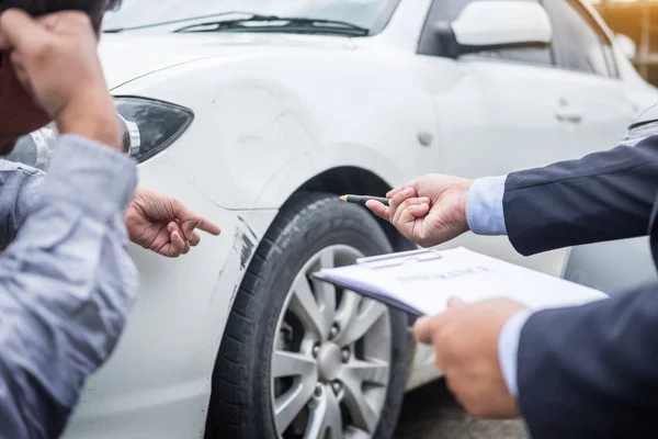 Försäkringsagent skriva Urklipp samtidigt undersöka bilen efter en — Stockfoto