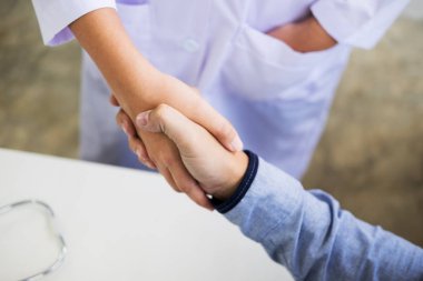 Doktor eller tıbbi ofiste glas giyen hastayla sallıyor