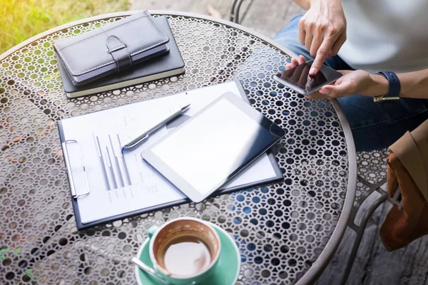 Kvinna med smart telefon och kaffe bredvid på ett träbord i g — Stockfoto