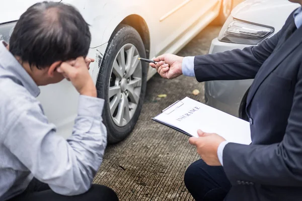 Agente de seguros que escribe en el portapapeles mientras examina el coche después de un — Foto de Stock