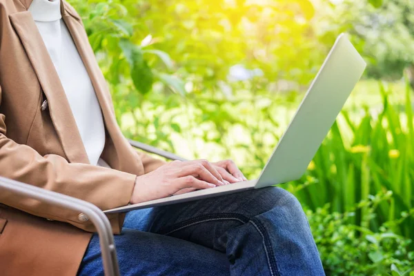 Ділова жінка рука використовує ноутбук на столі в саду . — стокове фото