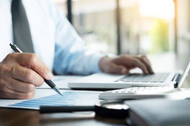 Ofiste çalışan işadamı bilgisayarında, tabletinde ve çalışma masasında veri dokümanlarıyla çalışıyor..