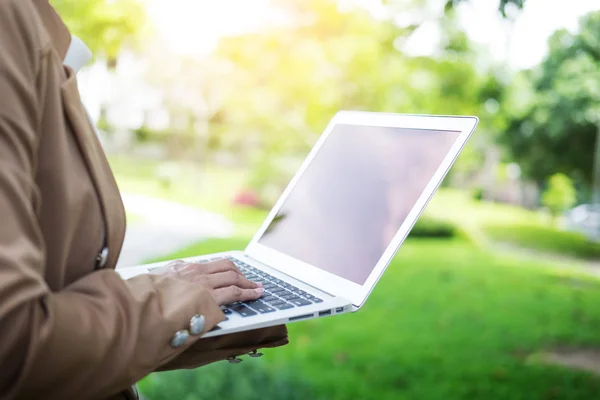 Ділова жінка рука використовує ноутбук на столі в саду . — стокове фото