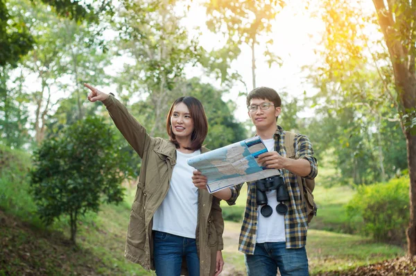 Pareja de turistas que se dirigen al bosque con mapas en la mano searc — Foto de Stock