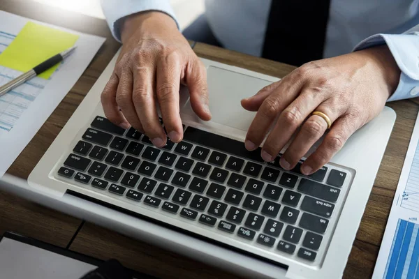 Бизнесмен, работающий в офисе с ноутбуком, планшетом и графиком — стоковое фото