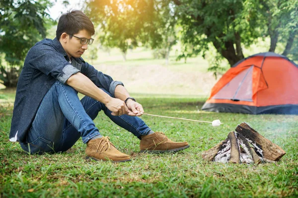 Чоловік переповнює свої зефірні цукерки на багатті на кампі — стокове фото