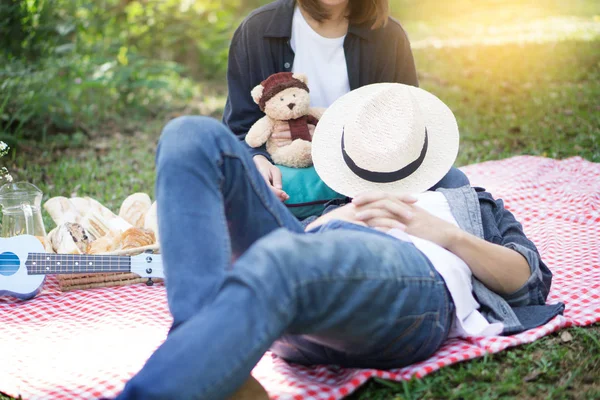 Casual stilig man sätta huvudet på knän, hustrun under picknick — Stockfoto