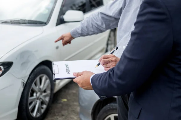 Agente de seguros que escribe en el portapapeles mientras examina el coche después de un — Foto de Stock