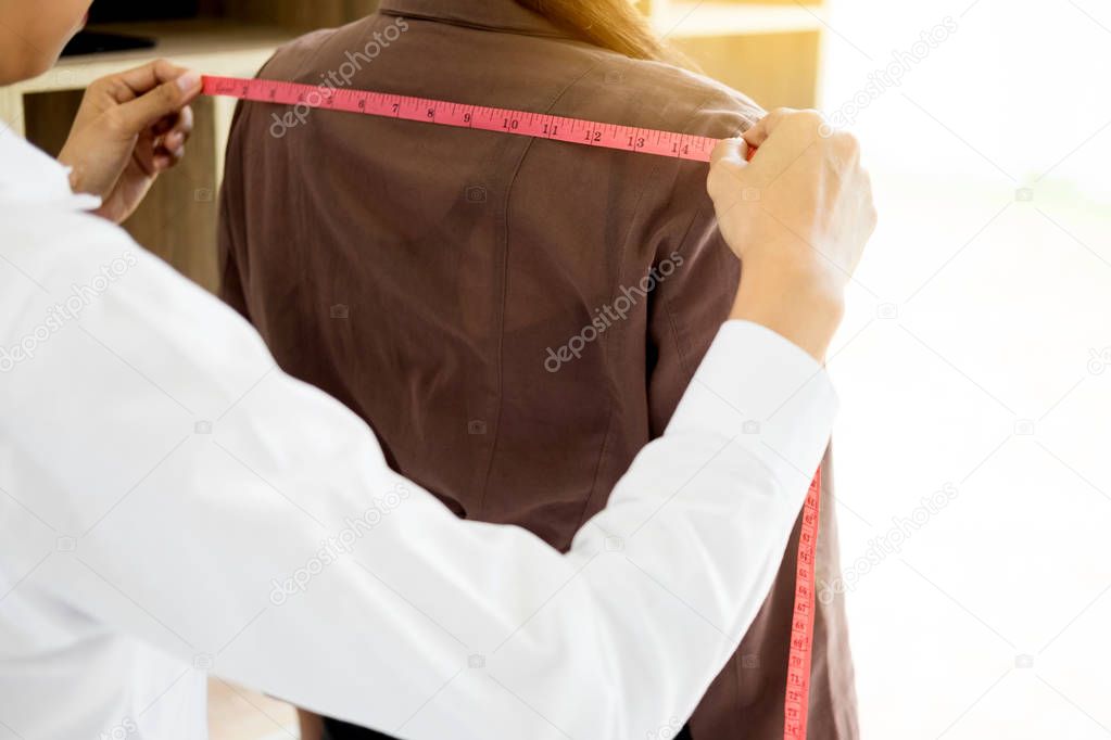 Fashion designer measuring on body part of women for a tailor ma