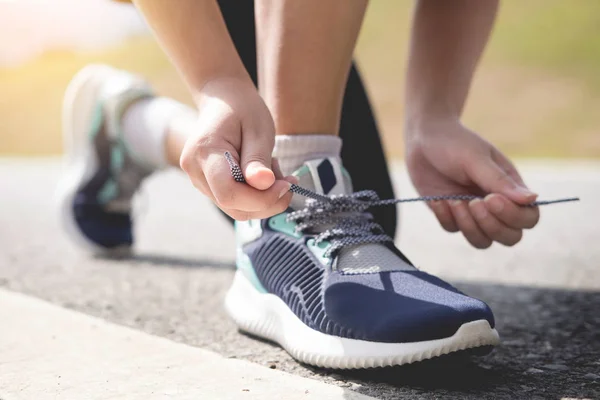 Recortado tiro de las mujeres jóvenes corredor apretando los cordones de zapato de correr —  Fotos de Stock
