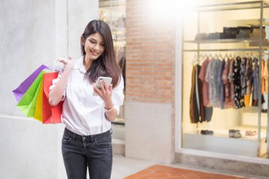 bir smartphone ayakta bir moda mağaza w tarafından kullanan güzel kadın