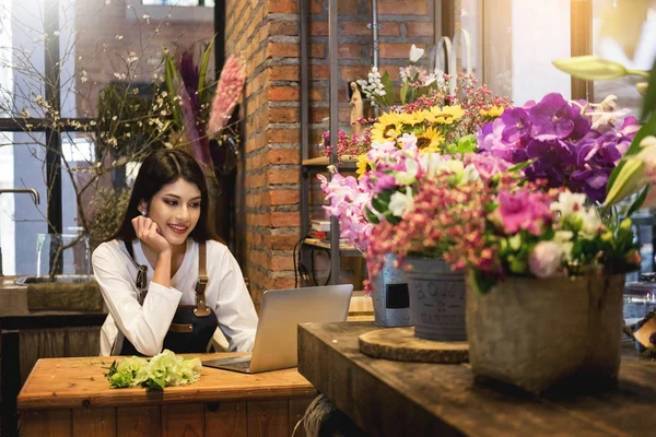Women florist looking laptop got order at counter of her flower
