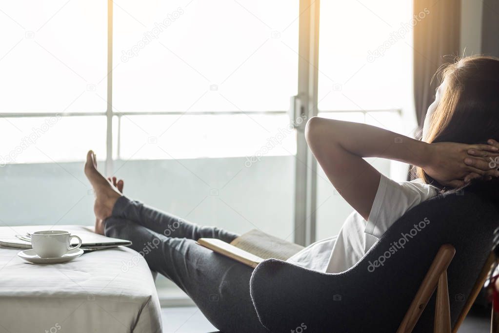 Woman reading book or newspaper and drinking coffee breakfast on bed during the morning