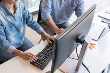 Masalarda oturan genç programcılar bilgisayarlar üzerinde çalışıyor 