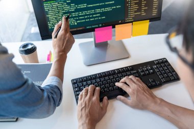Masalarda oturan genç programcılar bilgisayarlar üzerinde çalışıyor 