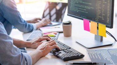 Masalarda oturan genç programcılar bilgisayarlar üzerinde çalışıyor 