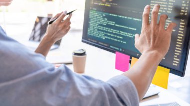 Masalarda oturan genç programcılar bilgisayarlar üzerinde çalışıyor 