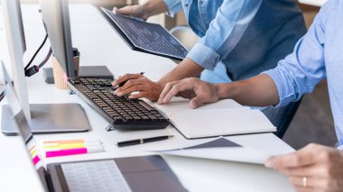 Masalarda oturan genç programcılar bilgisayarlar üzerinde çalışıyor 