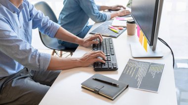 Masalarda oturan genç programcılar bilgisayarlar üzerinde çalışıyor 