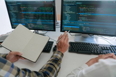 Masalarda oturan genç programcılar bilgisayarlar üzerinde çalışıyor 