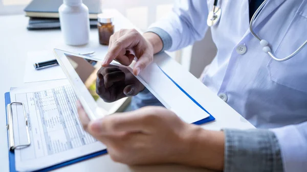 Doctor reading on a document report and writing on paperwork and — Stock Photo, Image