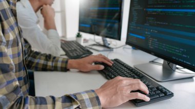 Masalarda oturan genç programcılar bilgisayarlar üzerinde çalışıyor 