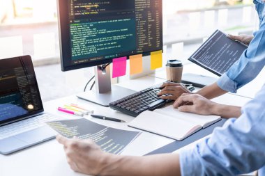 Masalarda oturan genç programcılar bilgisayarlar üzerinde çalışıyor 