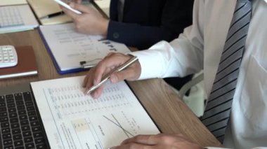 İş Adamları Toplantısı ve başarılı takım çalışması Konseptinde finansal belge grafikleri ve grafiklerini analiz eden iş arkadaşlarıyla sohbet ederken 4k video