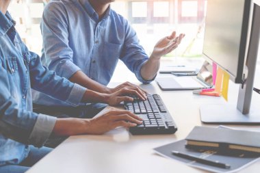 Masalarda oturan genç programcılar bilgisayarlar üzerinde çalışıyor 