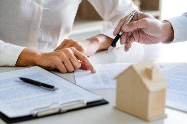 Gayrimenkul komisyoncusu ya da müteahhit danışman çalışana ev sözleşmesi satın almak için sözleşme gösteriyor
