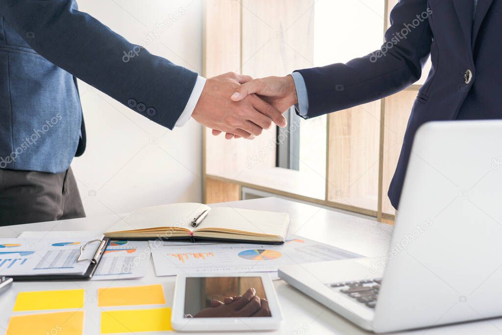 Good deal career and placement concept, successful young businessmen shaking hands after successful negotiation in modern office.