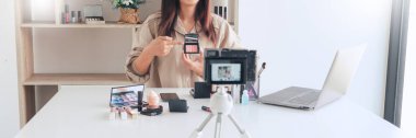Güzel Asyalı kadın profesyonel güzellik vlog 'u veya blog yazarı kozmetik sunar ve video kaydı için ön kameraya makyaj uygular