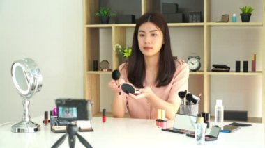 Ünlü blogcunun 4K videosu. Neşeli kadın vlogger makyaj dersleri için video kaydederken kozmetik ürünleri gösteriyor. iş yerinde.