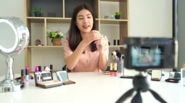 Ünlü blogcunun 4K videosu. Neşeli kadın vlogger makyaj dersleri için video kaydederken kozmetik ürünleri gösteriyor. iş yerinde.