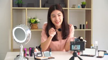 Ünlü blogcunun 4K videosu. Neşeli kadın vlogger makyaj dersleri için video kaydederken kozmetik ürünleri gösteriyor. iş yerinde.