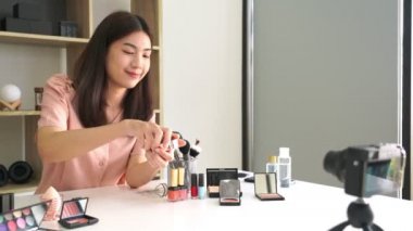 Ünlü blogcunun 4K videosu. Neşeli kadın vlogger makyaj dersleri için video kaydederken kozmetik ürünleri gösteriyor. iş yerinde.