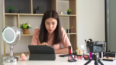 Ünlü blogcunun 4K videosu. Neşeli kadın vlogger makyaj dersleri için video kaydederken kozmetik ürünleri gösteriyor. iş yerinde.