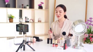 Ünlü blogcunun 4K videosu. Neşeli kadın vlogger makyaj dersleri için video kaydederken kozmetik ürünleri gösteriyor. iş yerinde.