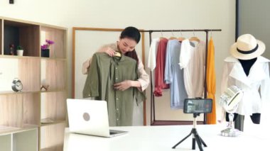 4k video: Çekici genç moda video blogcusu kameranın önünde oturmuş galeride moda ve giysi hakkında video kaydediyor.